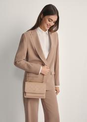 Beige women's handbag with monogram TOREC-1155-1A(W26), front view of the product on a model, half of the silhouette visible.