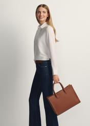 TORES-1206-1D(W26), camel-colored leather handbag. View of the product in the model's hand. Full-length silhouette visible.