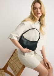 Small black leather women's handbag TORES-1263-99(W26) - front view of the product, held by the model, against a light background. Knee-length silhouette visible.