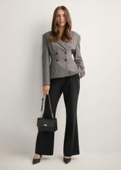 Small black women's handbag with an elegant clasp TOREC-1322-99(Z26), front view of the product on a model. Full body visible.