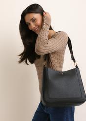 Black women's hobo bag TOREC-1257-9I(Z26), diagonal view of the product, on a model, on a light background. Half of the silhouette visible.