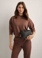 Black women's cosmetic bag TOREN-0267-9P(Z26), diagonal view of the product on the model. Half of the silhouette visible.