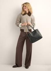 Black women's shopper bag TOREC-1344-9I(Z26), view of the product in the model's hand. Full body visible.