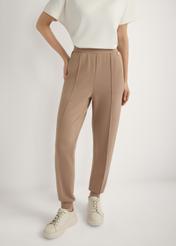 Caramel tapered trousers SPODT-0104 A-1D(W26), front view of the product on the model. Half of the silhouette visible.