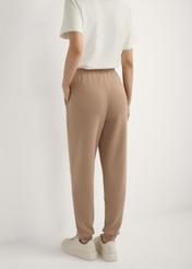 Caramel tapered trousers SPODT-0104 A-1D(W26), back view of the product on the model. Half of the silhouette visible.