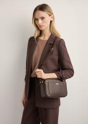 Brown women's handbag with monogram TOREC-1290-1I(Z26), diagonal view of the product on the model. Half of the silhouette visible.