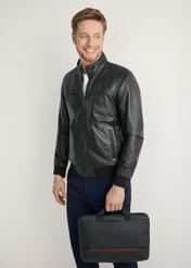 Black TORMN-0398-9J(W26) laptop bag - front view of the product, held by the model, against a light background. Knee-length silhouette visible.