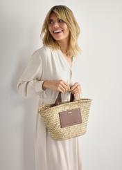 Women's straw basket bag TOREC-0945-1E(W26) - front view of the product, held by the model, against a light background. Half-length silhouette visible.