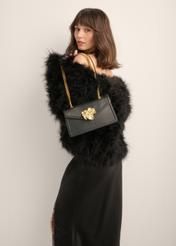 Black leather handbag with decorative element TORES-1394-99(Z26) - front view of the product, held by the model, against a light background. Half of the silhouette is visible.