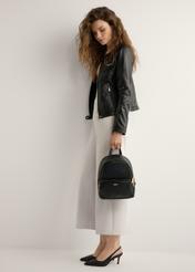 Black women's backpack made of imitation leather TOREC-1014-99(W25), product view from the front on a model, the whole silhouette is visible.