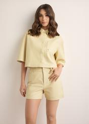 Women's short light yellow leather shirt KOSDS-0005-2A(W26), front view of the product on the model. Half of the silhouette visible.