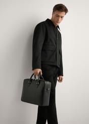 Black leather men's briefcase TORMS-0507-99(W26) - diagonal view, held by the model, against a light background. The silhouette is visible to the knees.