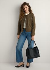 Black women's shopper bag TOREC-1183-99(W26) - slightly diagonal view of the product, held by the model, against a light background. The entire silhouette is visible.