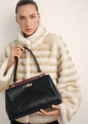 Black women's shoulder bag TOREC-1376-99(Z26), view of the product in the model's hands, on a light background.
