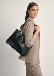 Black large women's handbag TOREC-0998-9F(W26), front view of the product on a model, half of the silhouette visible.