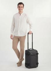 Small suitcase on wheels WALNY-0047-99-19(W26), diagonal view of the product next to the model's silhouette.