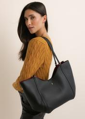 Black women's shopper bag TOREC-1296-9I(Z26), front view of the product, on a model, on a light background. Half silhouette visible.