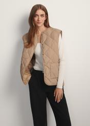 Beige women's quilted vest KAMDT-0035-1C(W26), front view of the product on the model. Half of the silhouette visible.