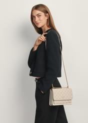 Cream women's monogram messenger bag TOREC-1156-0P(W26) - front view of the product, with the model standing sideways against a light background. Half of the silhouette visible.