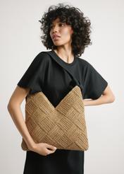 Beige women's natural fiber handbag TOREC-1039-1E(W26) - front view of the product, held by the model, against a light background. Knee-length silhouette visible.