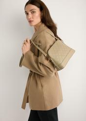 Beige women's monogram handbag TOREC-1180-1P(W26) - slightly diagonal view of the product, held by the model, against a light background. Half of the silhouette is visible.