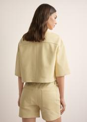 Women's short light yellow leather shirt KOSDS-0005-2A(W26), back view of the product on the model. Half of the silhouette visible.
