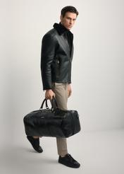 Black leather men's travel bag TORMS-0481-99(Z25) - diagonal view of the product, held by the model. Full body visible.