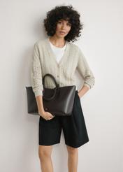 Brown women's shopper bag TOREC-1240-1H(W26), product view in model's hands. Half of silhouette visible.