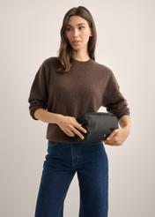 Black women's cosmetic bag TOREN-0348-99(Z26), diagonal view of the product on the model. Half of the silhouette visible.