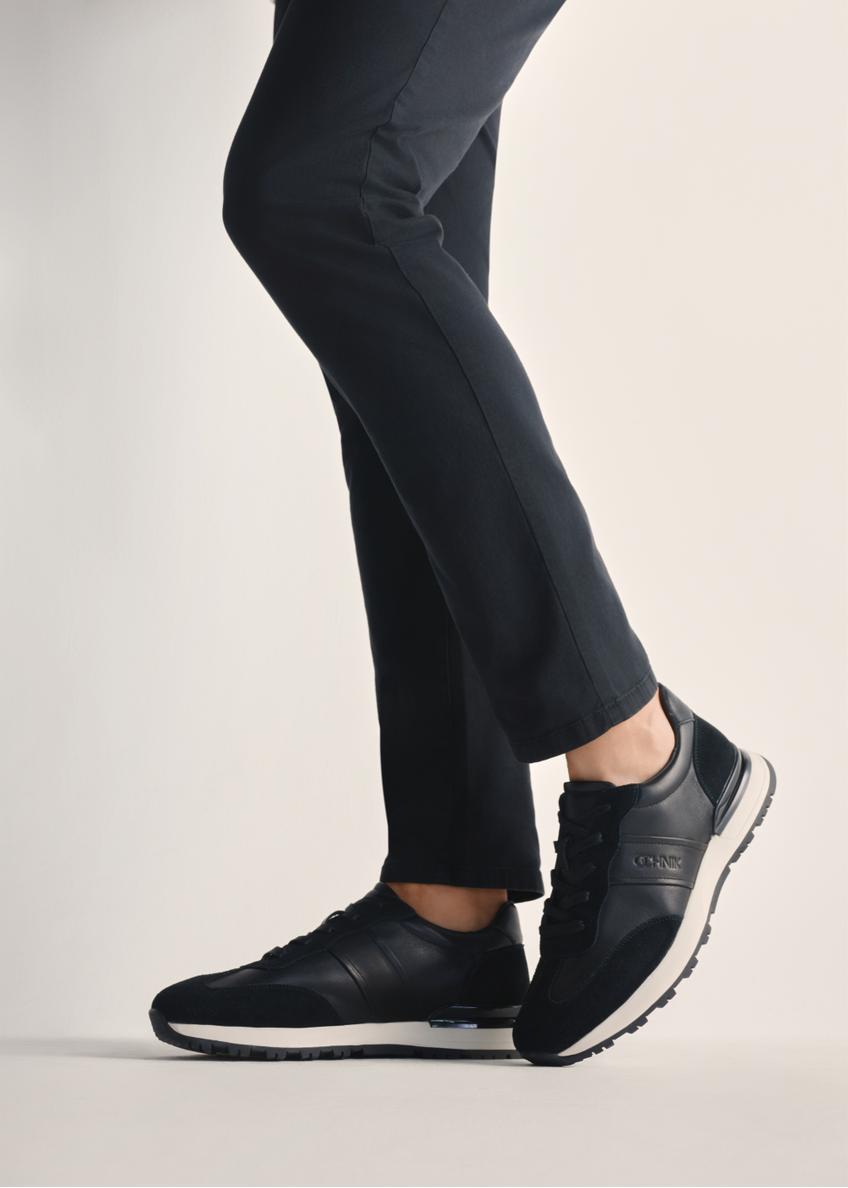 Black men's sports shoes BUTYM-0510-99(Z25), product view on model's feet against a light background.