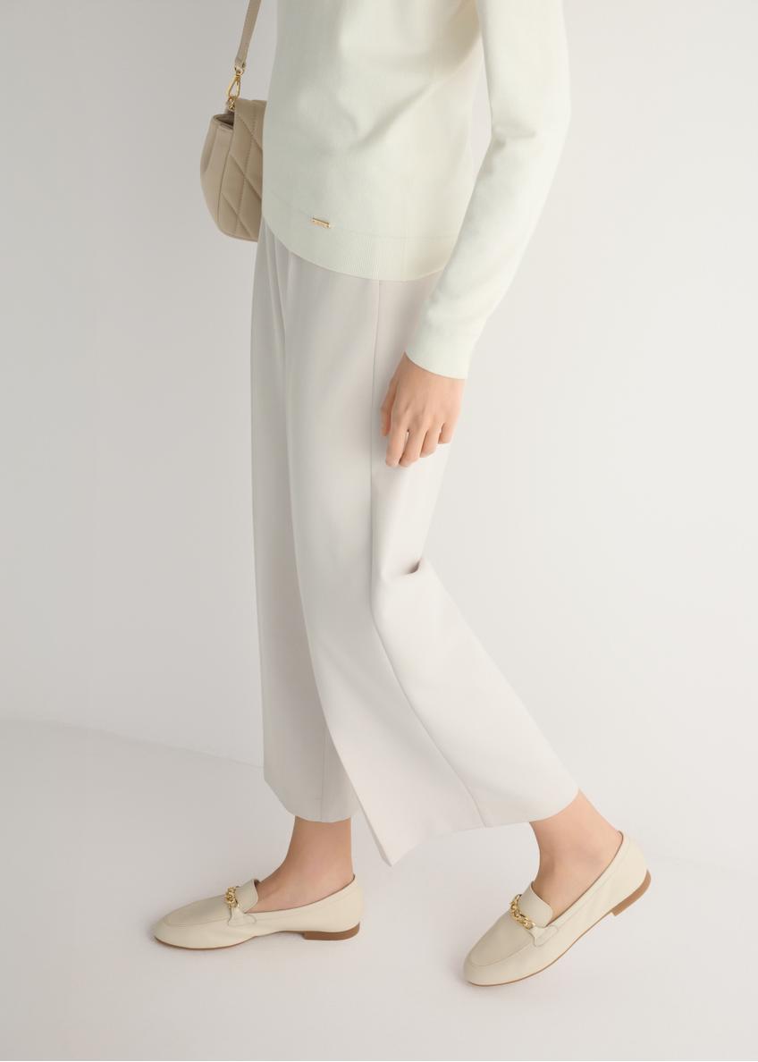 Women's cream leather moccasins with chain BUTYD-0914A-0B(W26), side view of the product on the model, half of the silhouette visible.