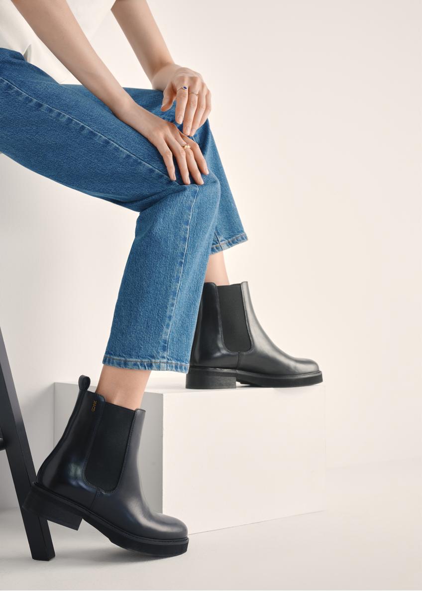 Women's black leather Chelsea boots BUTYD-1196-99(Z25) - side view of the product on a model against a white background. Knee-length silhouette visible.