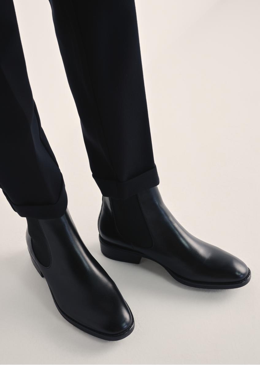 Black leather women's ankle boots BUTYD-0936A-99(Z25), product view on model's feet against a light background.