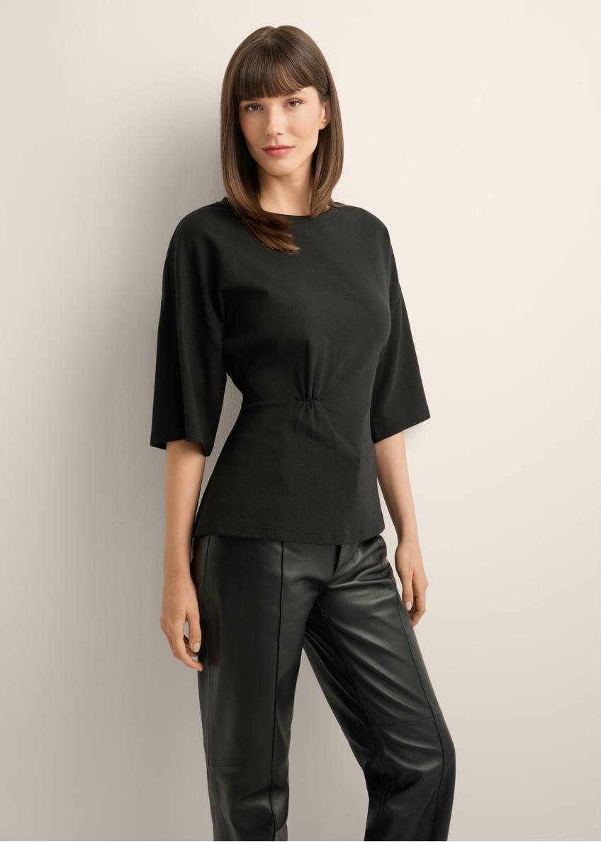 Black women's blouse with draping TSHDT-0163-99(Z26), front view of the product on the model, half of the silhouette visible.