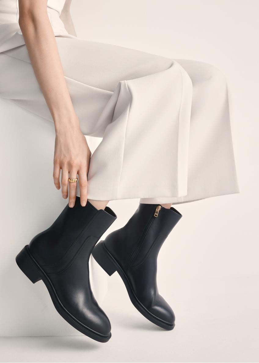 Black leather women's ankle boots BUTYD-1033-99(Z25), product view on model's feet against a light background.