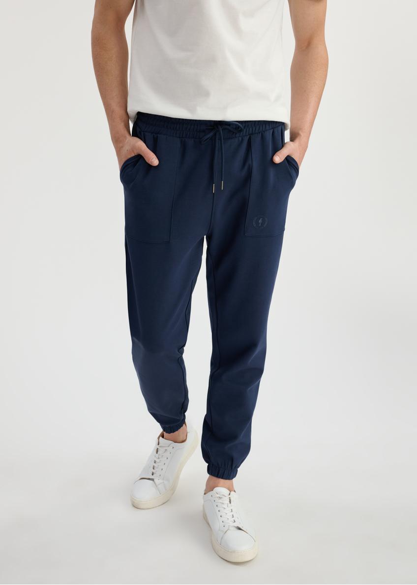Navy blue men's sweatpants SPOMT-0109-69(W25) - front view on model on white background. Half of the silhouette visible.